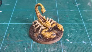 Painted Greater Mutant Scorpion miniature alongside for 28mm scale games — front-right view