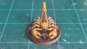 Painted Greater Mutant Scorpion miniature alongside for 28mm scale games — front view