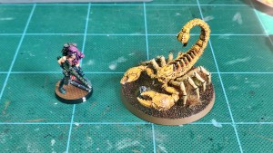 Painted Greater Mutant Scorpion miniature alongside a 28mm scale human miniature (1)
